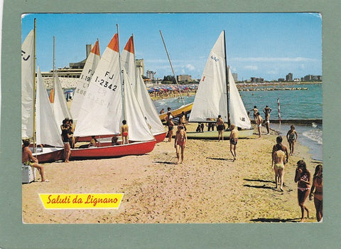 AK Saluti da Lignano. Barche a vela sulla grande spiaggia dorata.